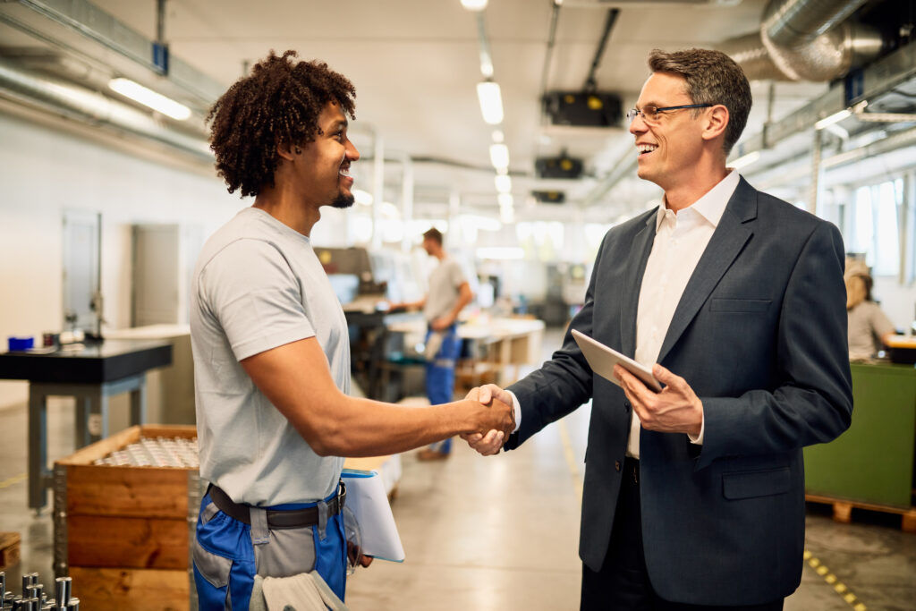 happy manager and african american steel worker shaking hands in